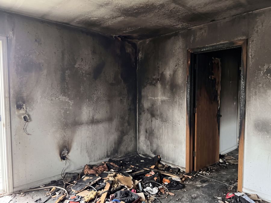 A fire damaged interior corner with charred walls and soot